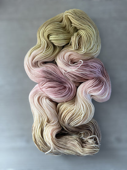 Ethically sourced merino wool yarn in dusty pink, golden yellow, and light tan watercolor shades.
