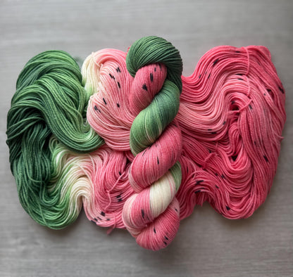 Yarn skeins designed to look like watermelon on a gray background