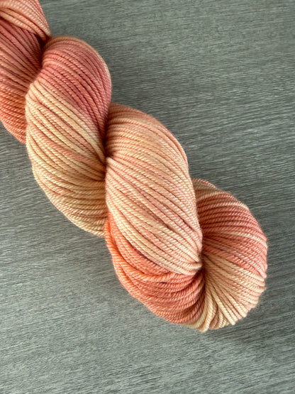 Ethically sourced merino wool yarn, hand-dyed in soft peach, ivory, and light rose hues.