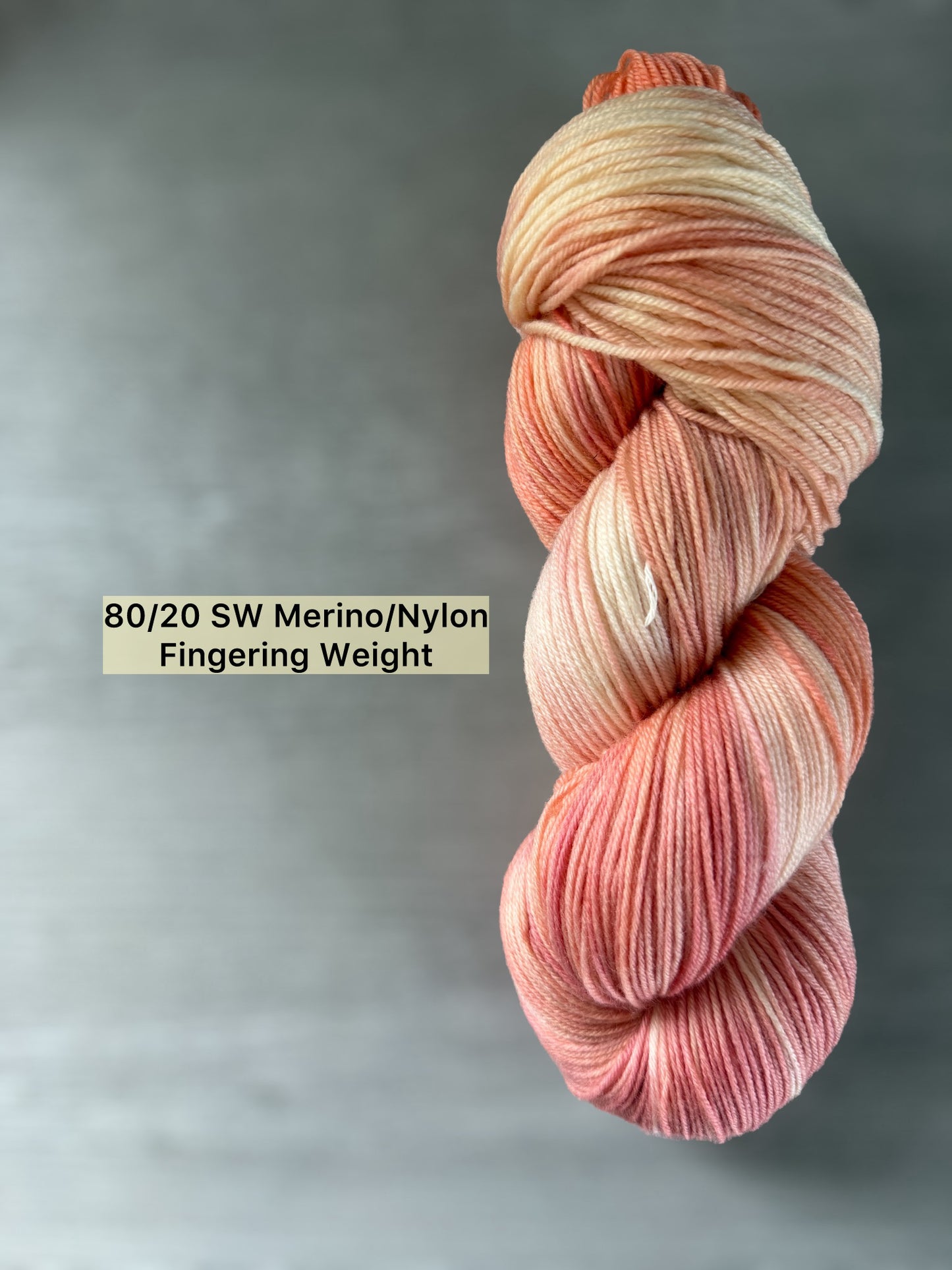 Hand-dyed ethically sourced merino wool yarn in soft peach, ivory, and rose, Fingering Weight.