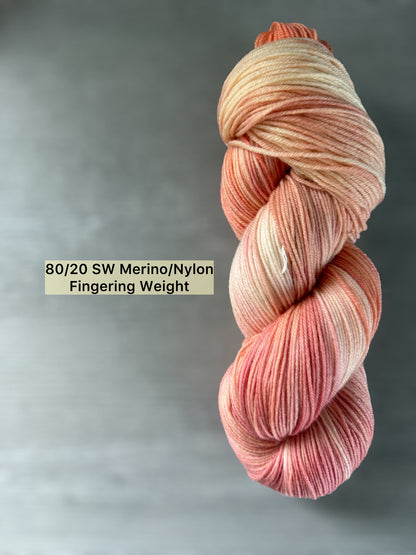 Hand-dyed ethically sourced merino wool yarn in soft peach, ivory, and rose, Fingering Weight.