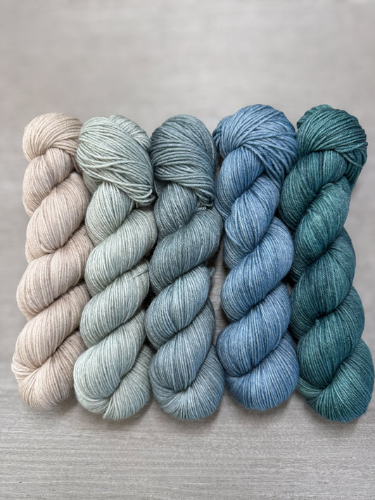Ethically sourced merino wool mini skeins in soft sage, muted blues, and forest greens.