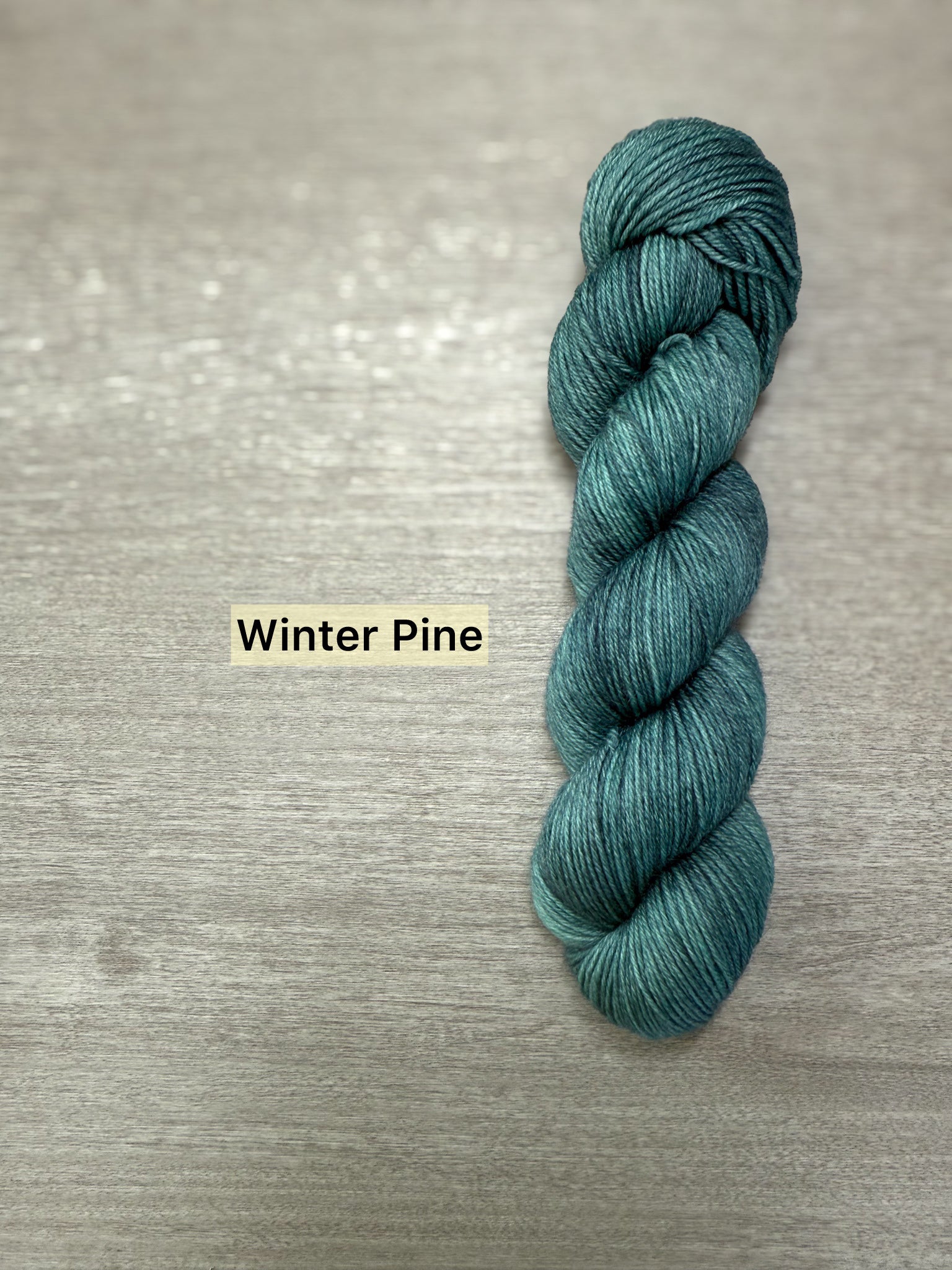 Ethically sourced hand-dyed merino wool yarn in a deep forest green, "Winter Pine" shade.