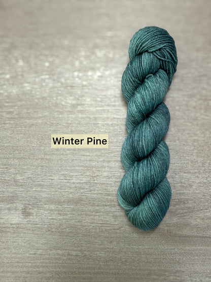 Ethically sourced hand-dyed merino wool yarn in a deep forest green, "Winter Pine" shade.